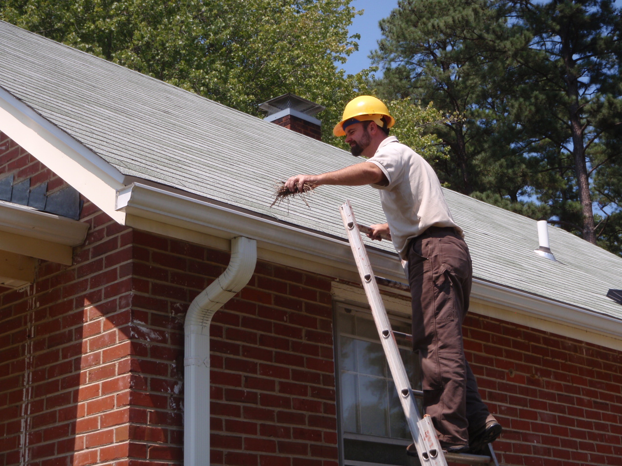 Inspector on a ladder at a roof edge